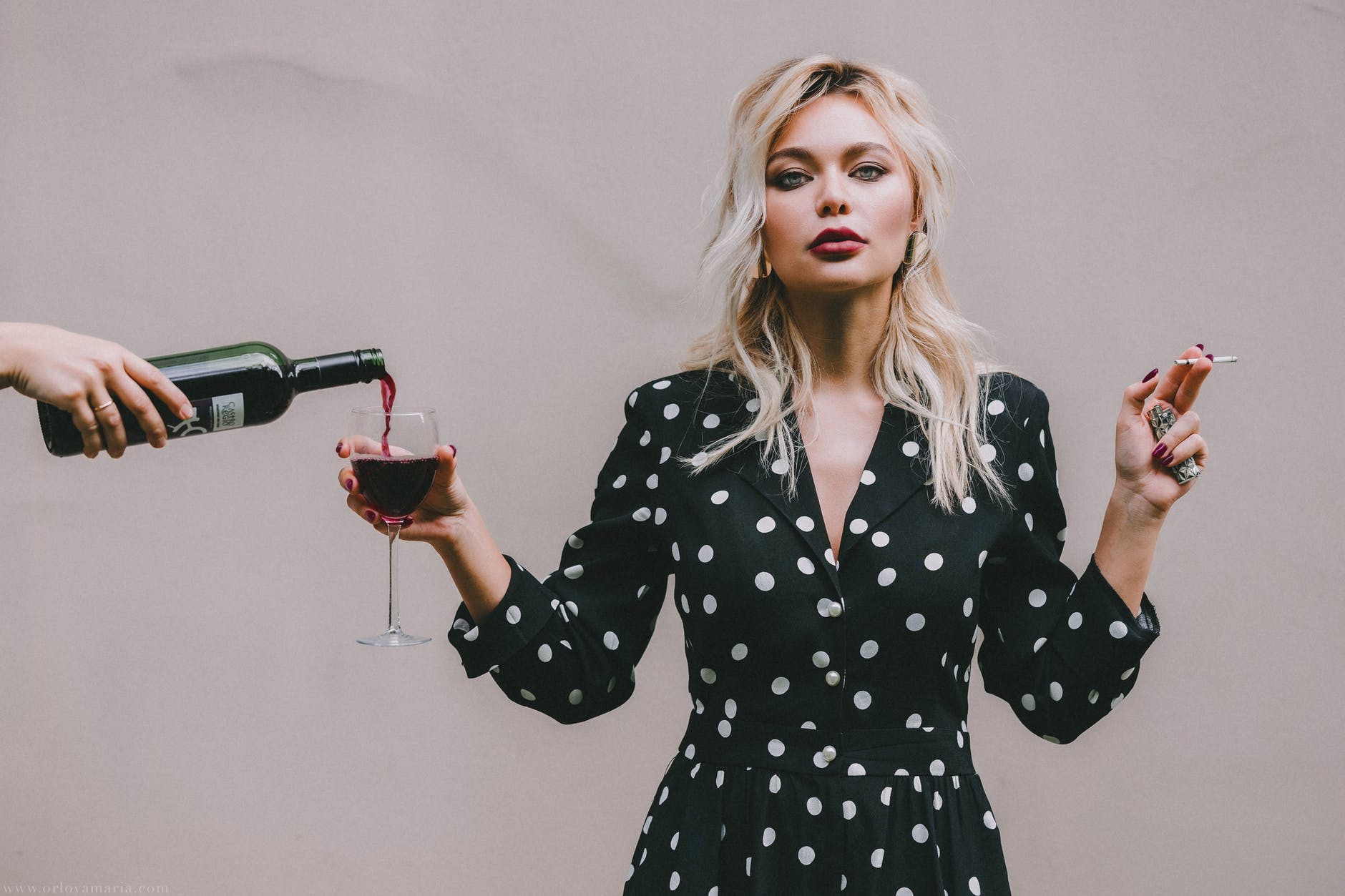 confident woman standing with wineglass and cigarette