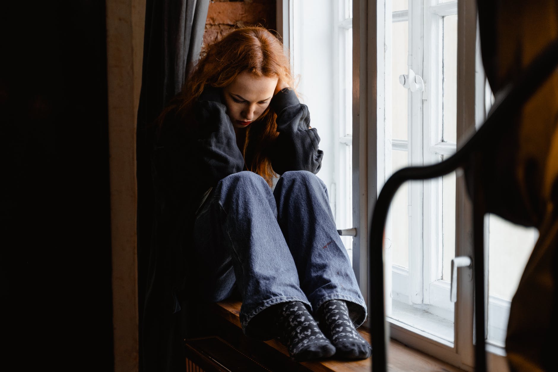 depressed woman sitting by the window