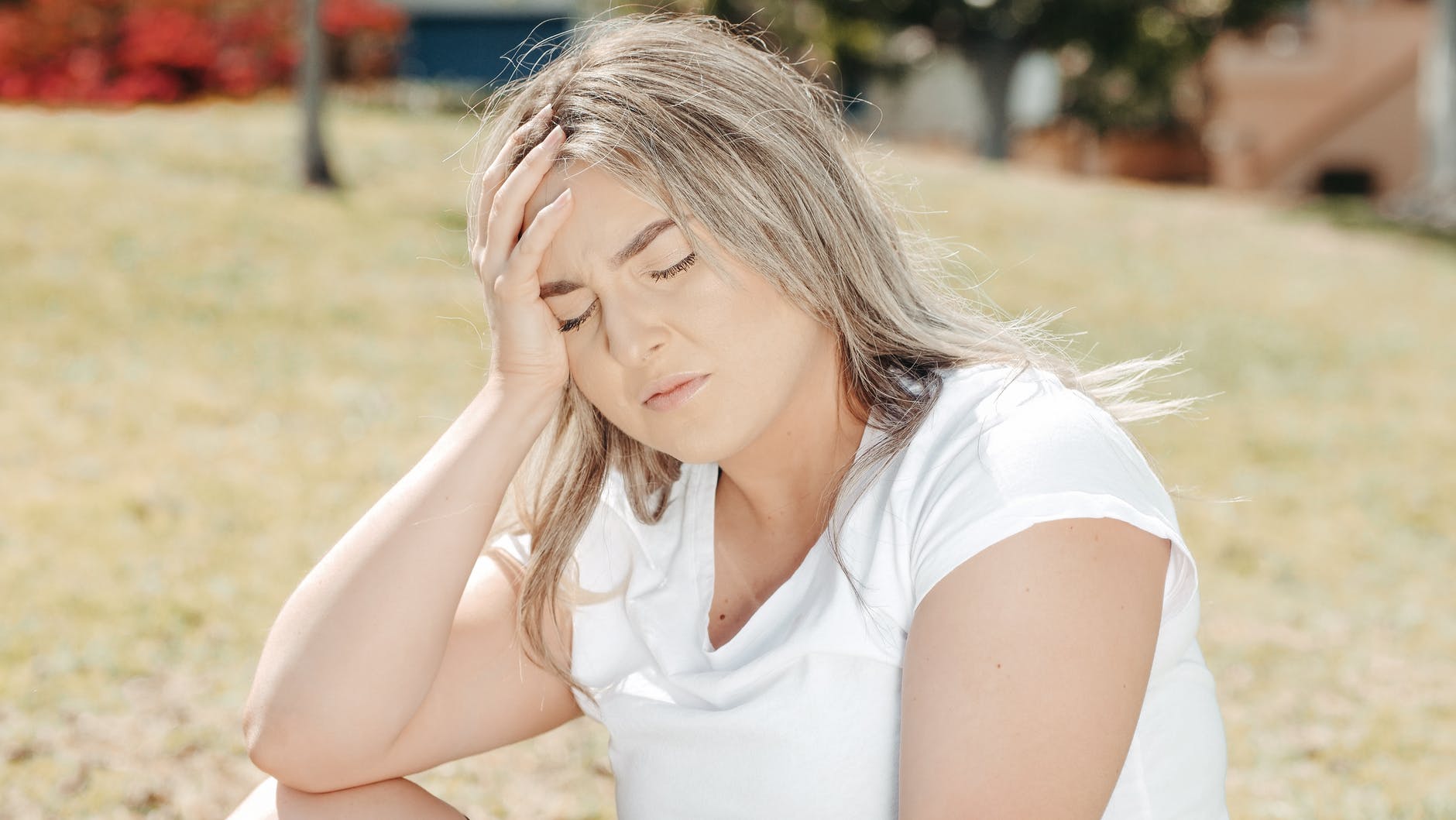 a woman in white shirt with her hand on her head